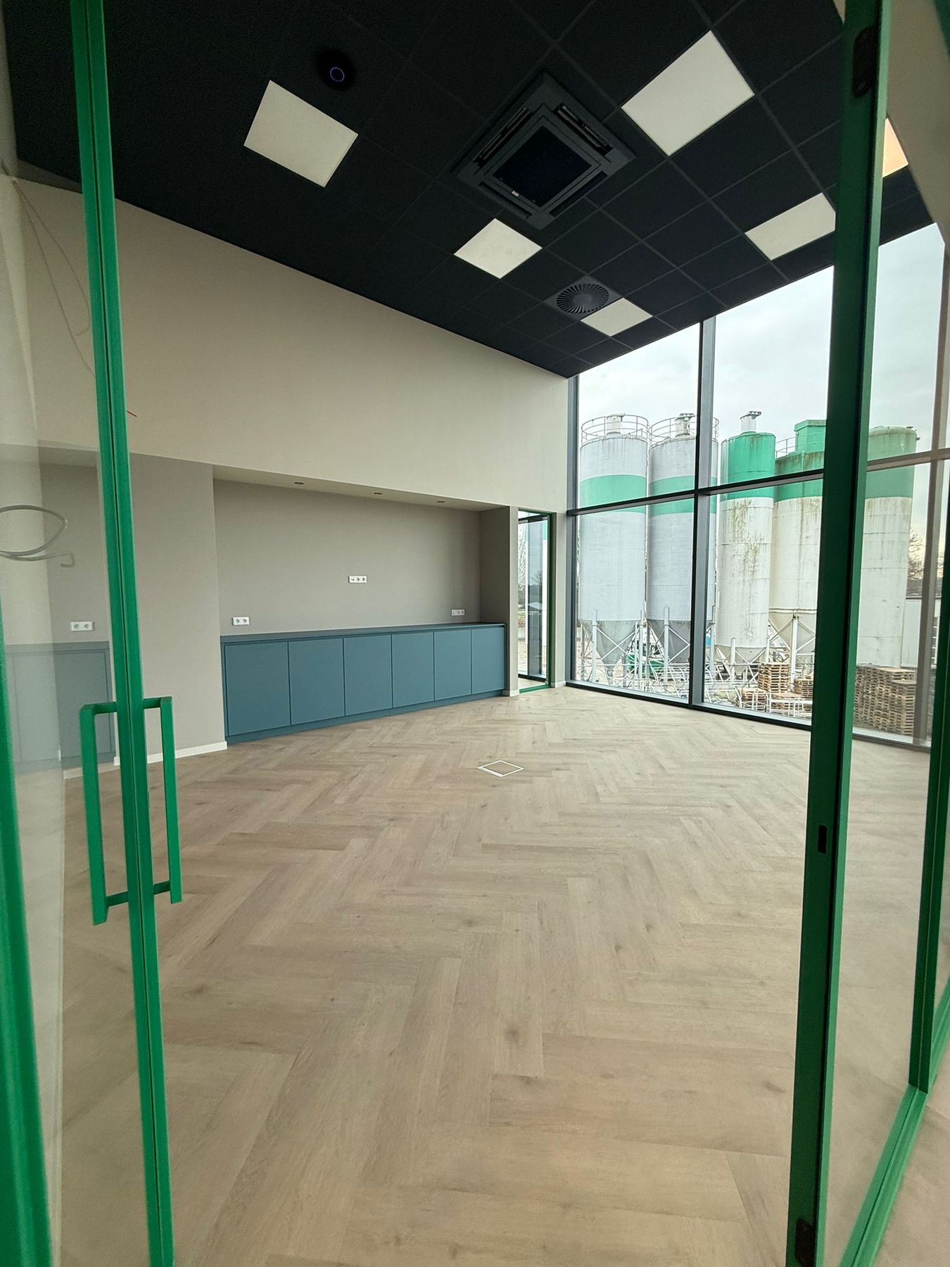 Een interieurproject met visgraatvloer en glazen deuren met groene kozijnen